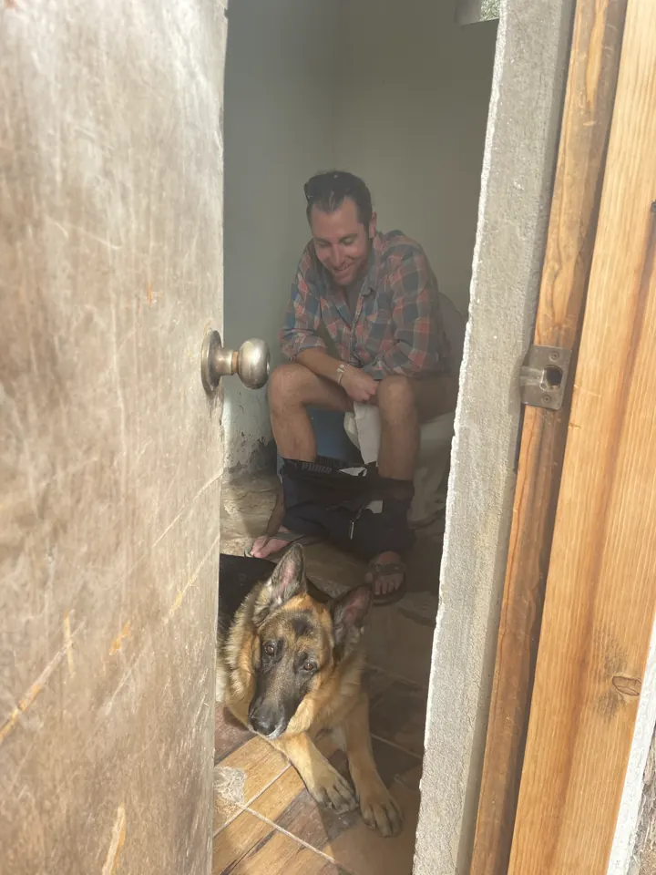 Colin peeking out of a wooden doorway with Jack, our German Shepherd, beside him