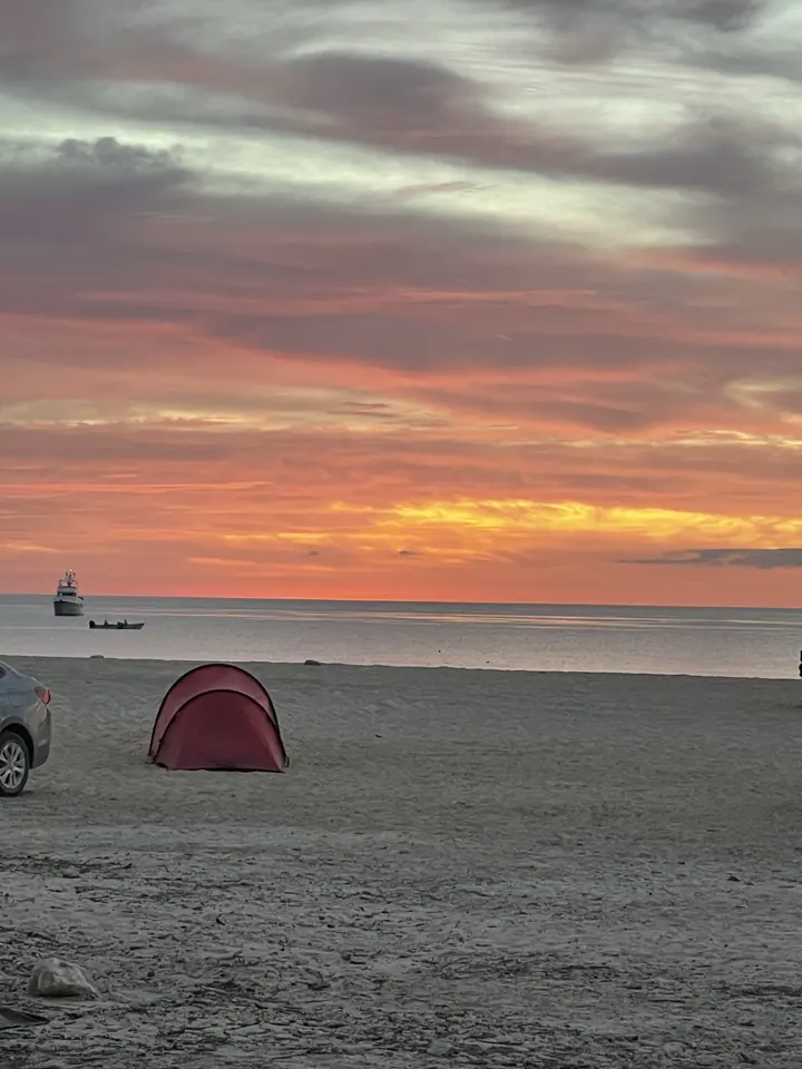 Colorful sunset over the sea with a small tent on the beach