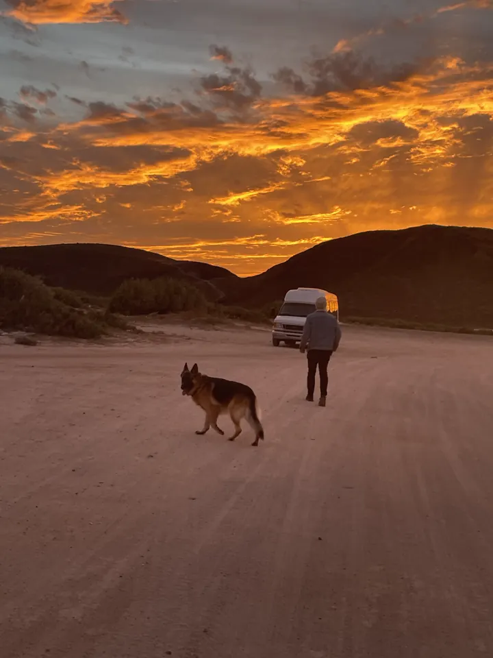 Colin and Jack, our German Shepherd, on a sandy flat under a fiery orange sunset