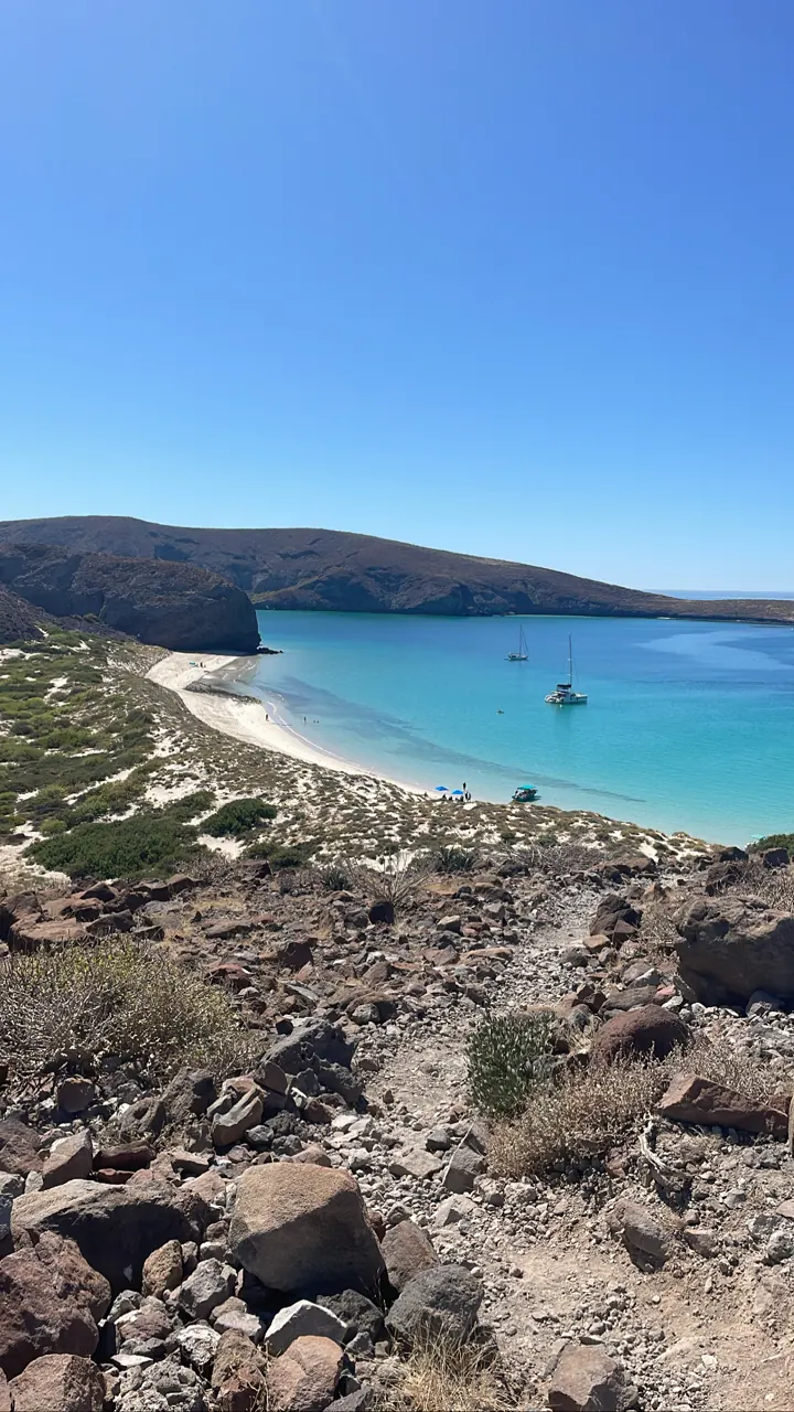 Turquoise cove and white beach seen from a rocky hillside