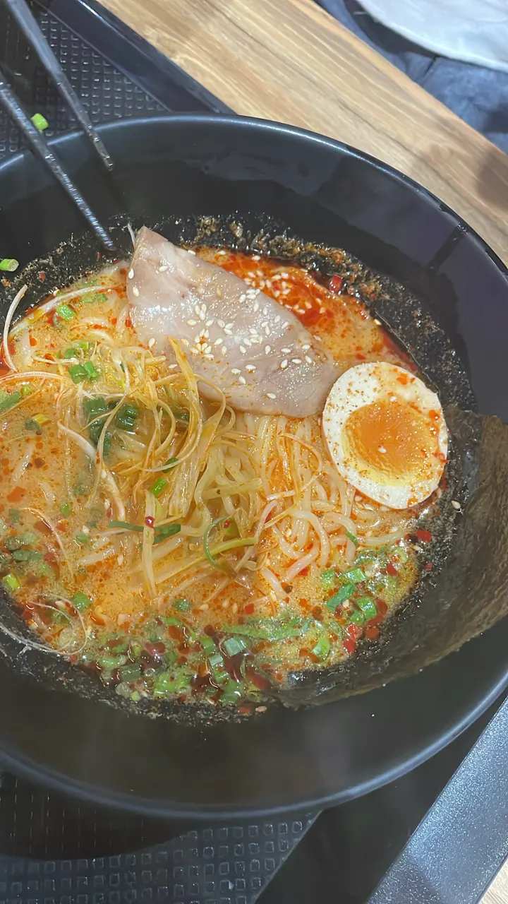 Bowl of noodle soup with a halved soft-boiled egg and toppings