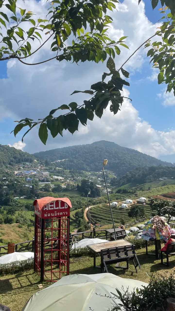 Green hills and valley seen from a cafe garden with a red phone booth
