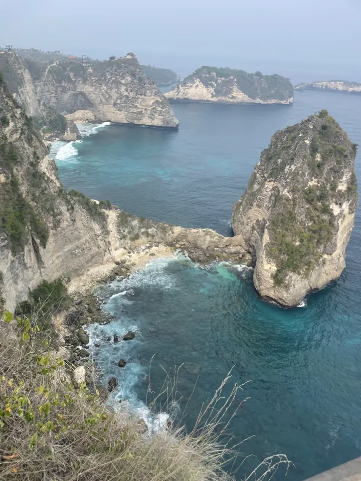 Rocky sea stacks and cliffs above a deep blue bay