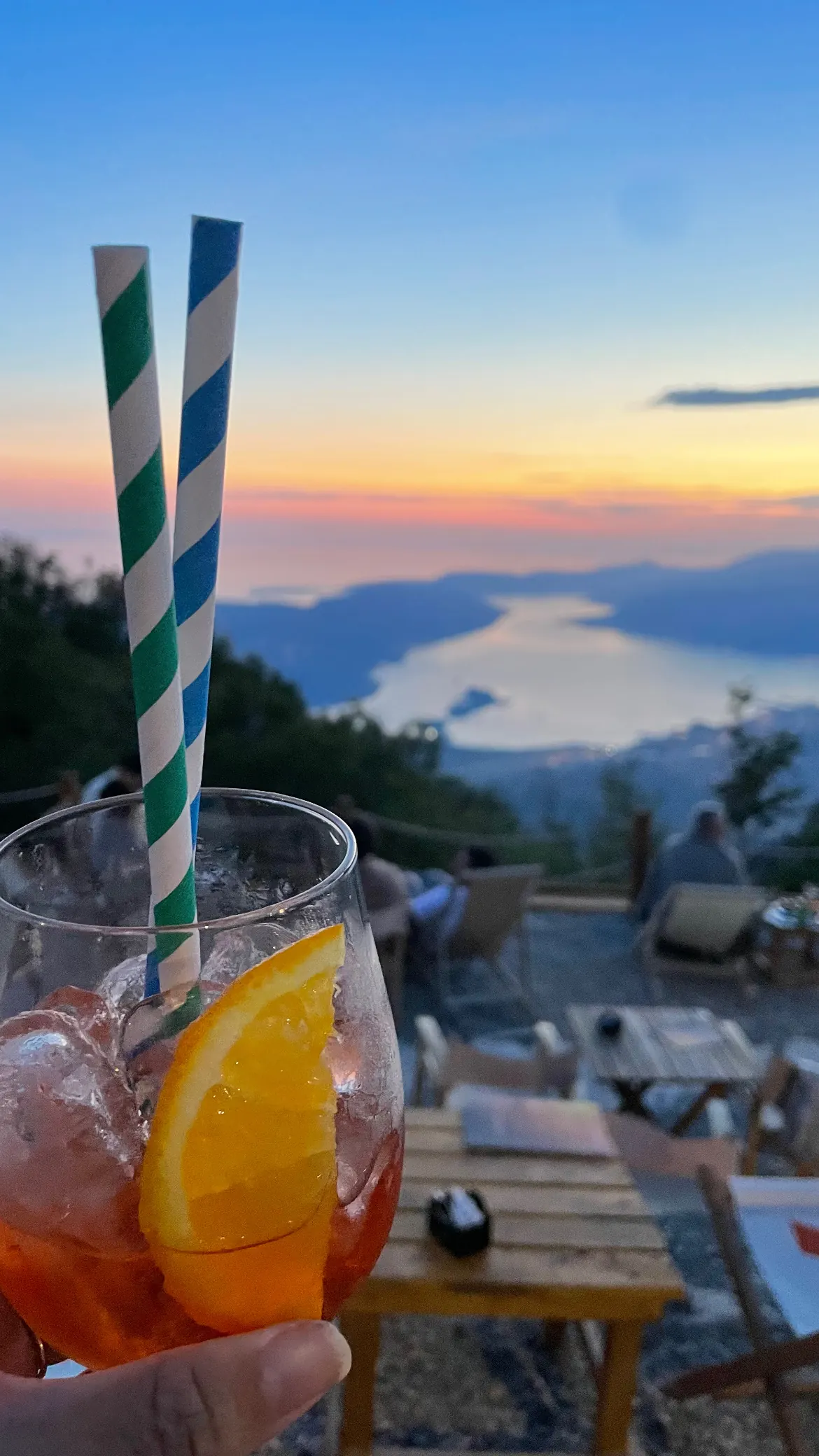 An Aperol spritz at sunset with the bay far below
