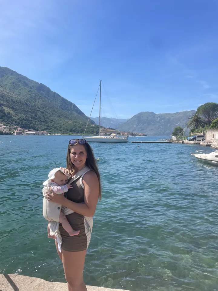 Angela holding Andi by the turquoise water of the bay
