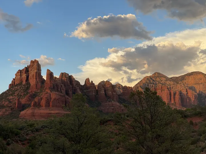 Sedona's red rock formations glowing at golden hour under scattered clouds