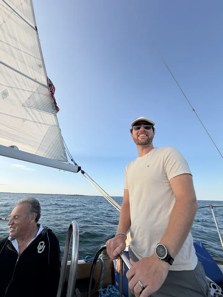 Colin at the wheel of a sailboat