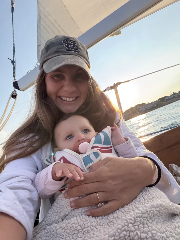 Angela holding a bundled-up Andi on a sailboat