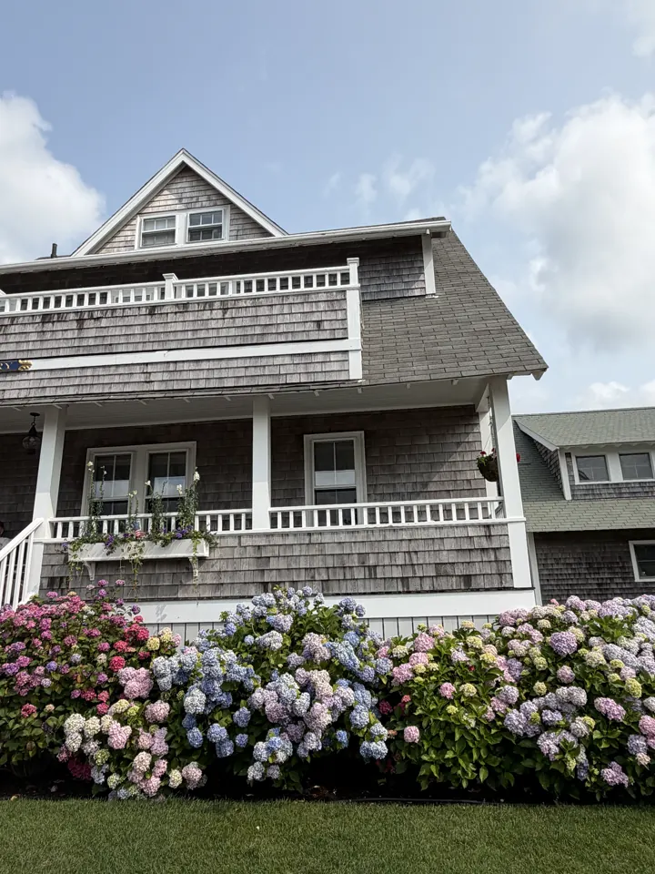 A classic shingled Nantucket house with a porch and flowers