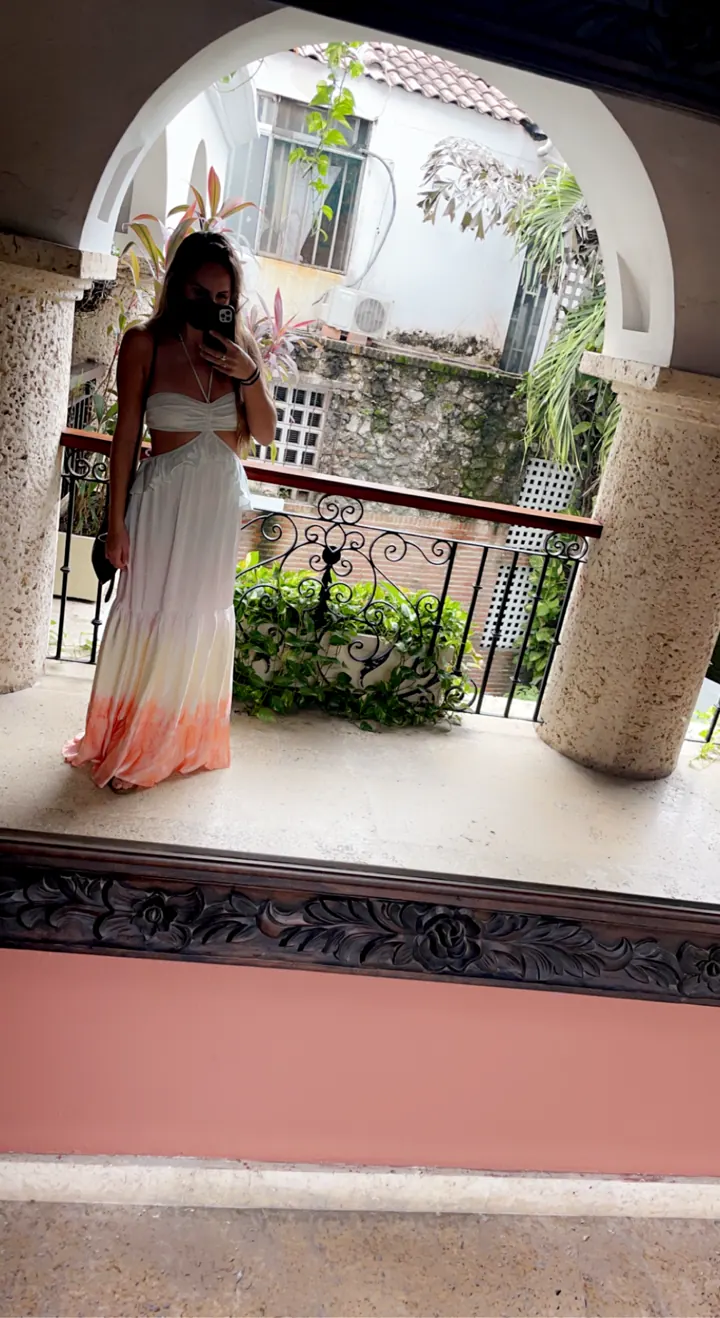 A woman in a long dress standing in an arched colonial courtyard