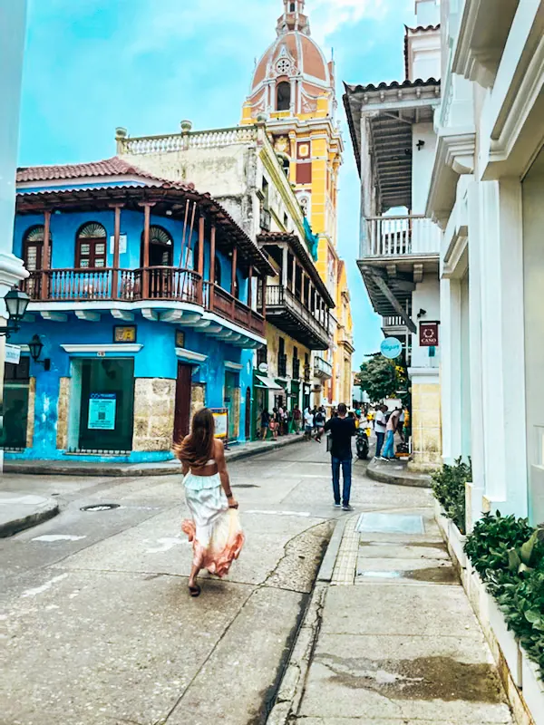 A woman walking down a bright street toward the Clock Tower