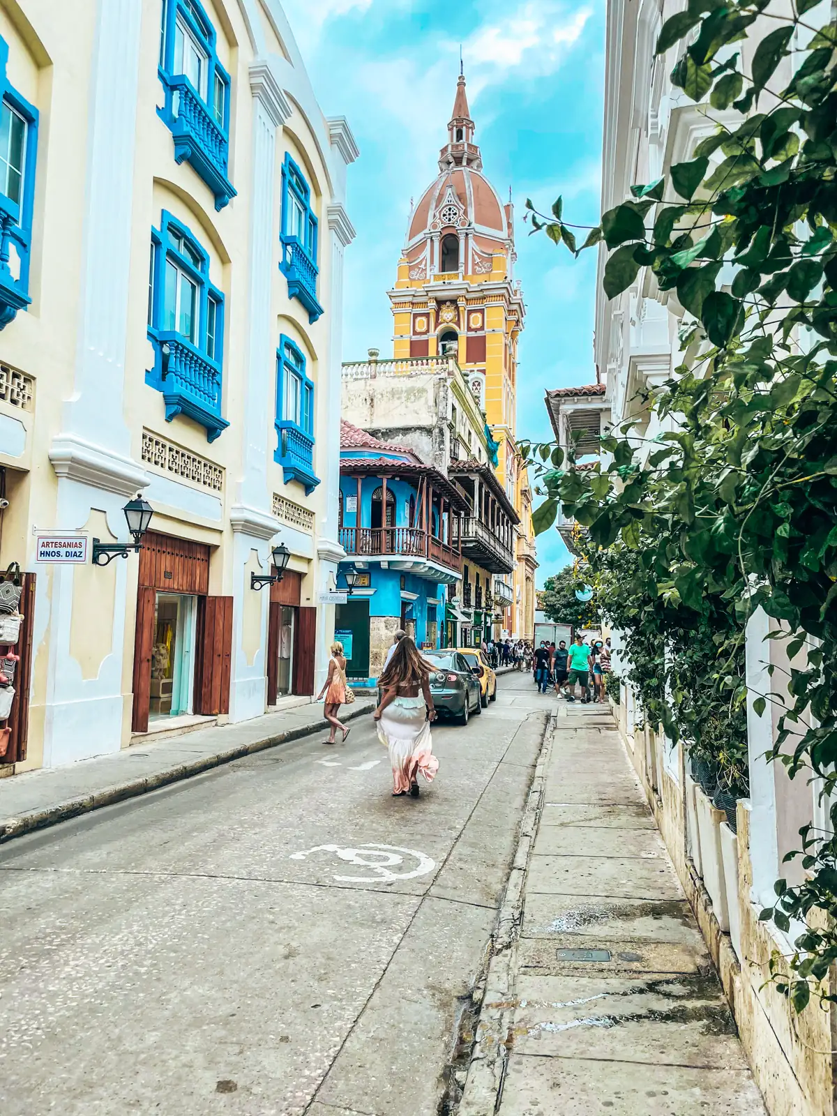 A colorful colonial street in Cartagena's old city leading to a church dome
