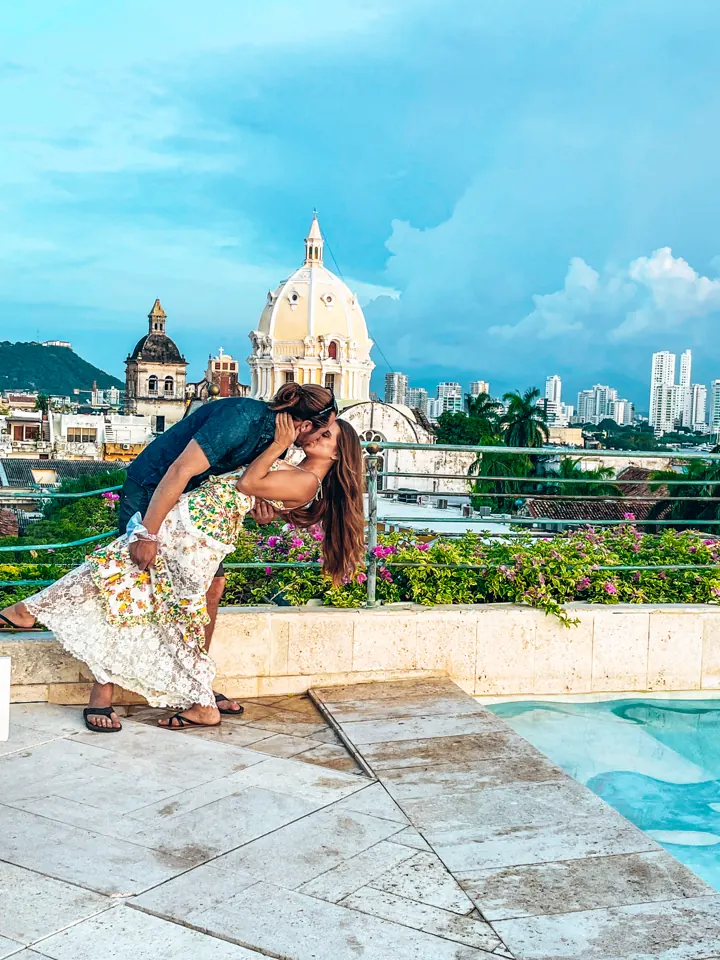 A couple sharing a dip kiss on a rooftop terrace with a church dome and city skyline behind