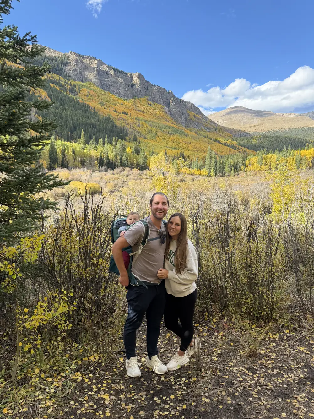 Colin and Angela standing among golden aspens on a mountain hillside