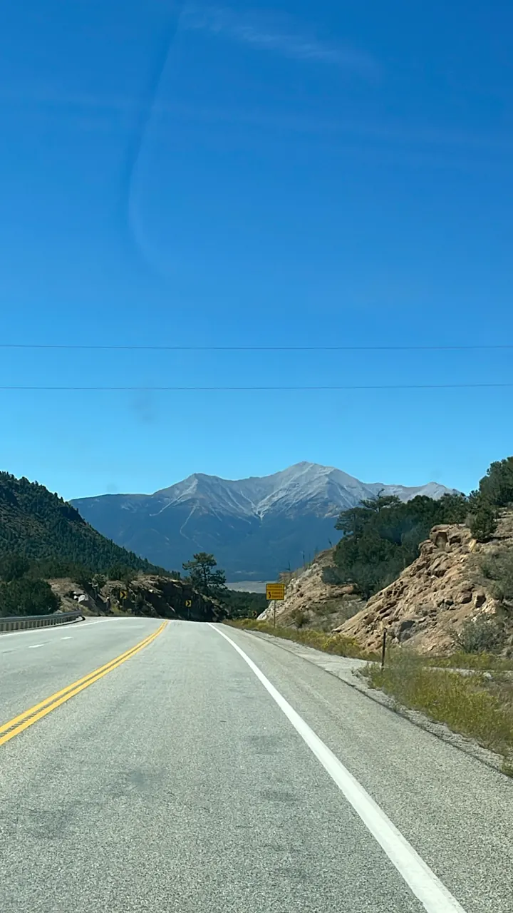 Empty highway curving toward distant mountains under blue sky