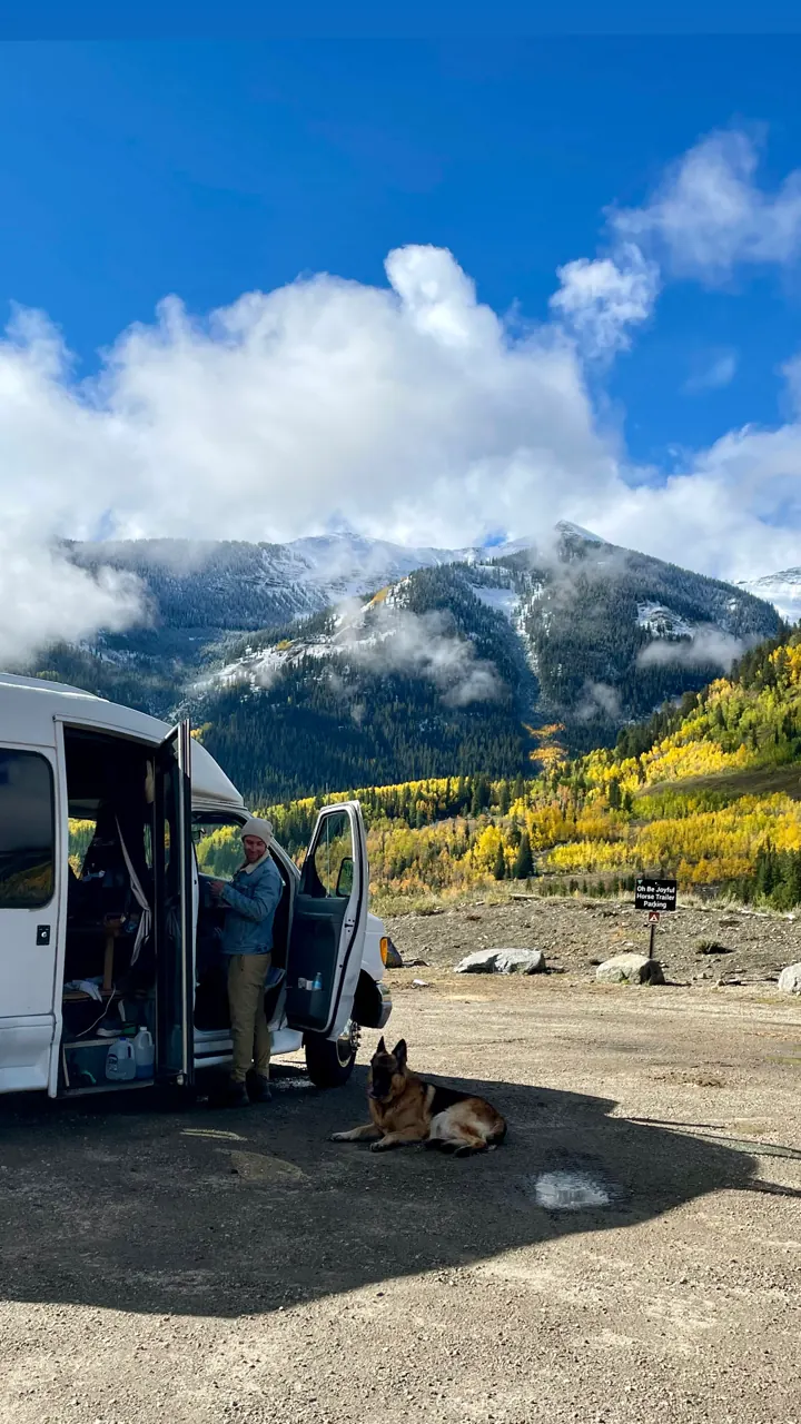 Our camper van parked at a mountain pullout with snowy peaks and fall color
