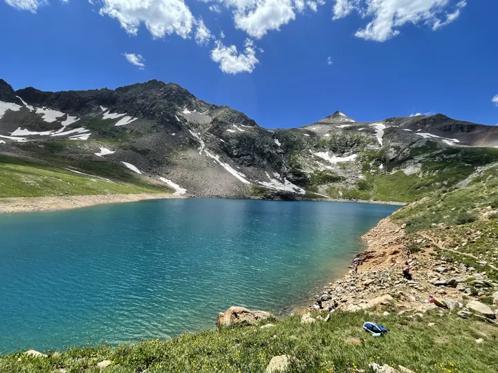 Blue alpine lake ringed with snowfields and peaks
