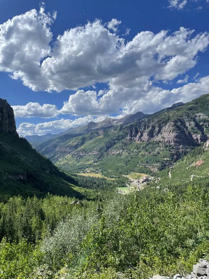 Green valley and red cliffs of Telluride under puffy clouds