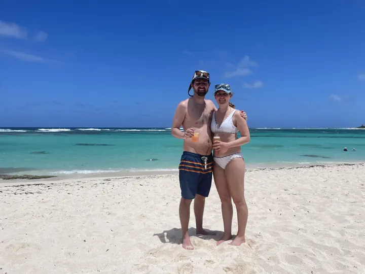 A couple standing on a white-sand beach with turquoise water