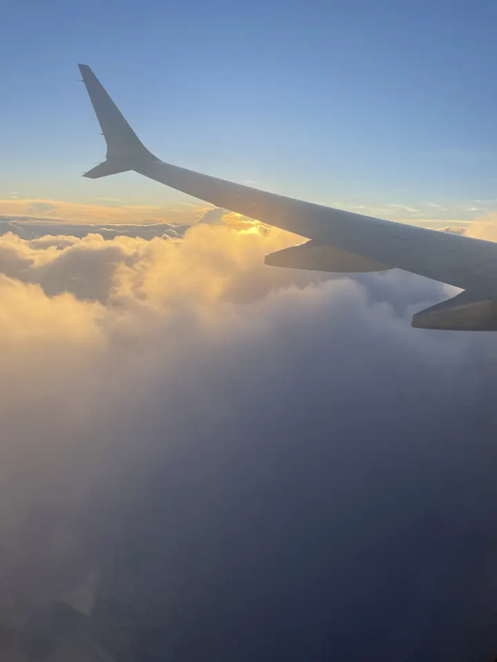 An airplane wing above clouds at sunset