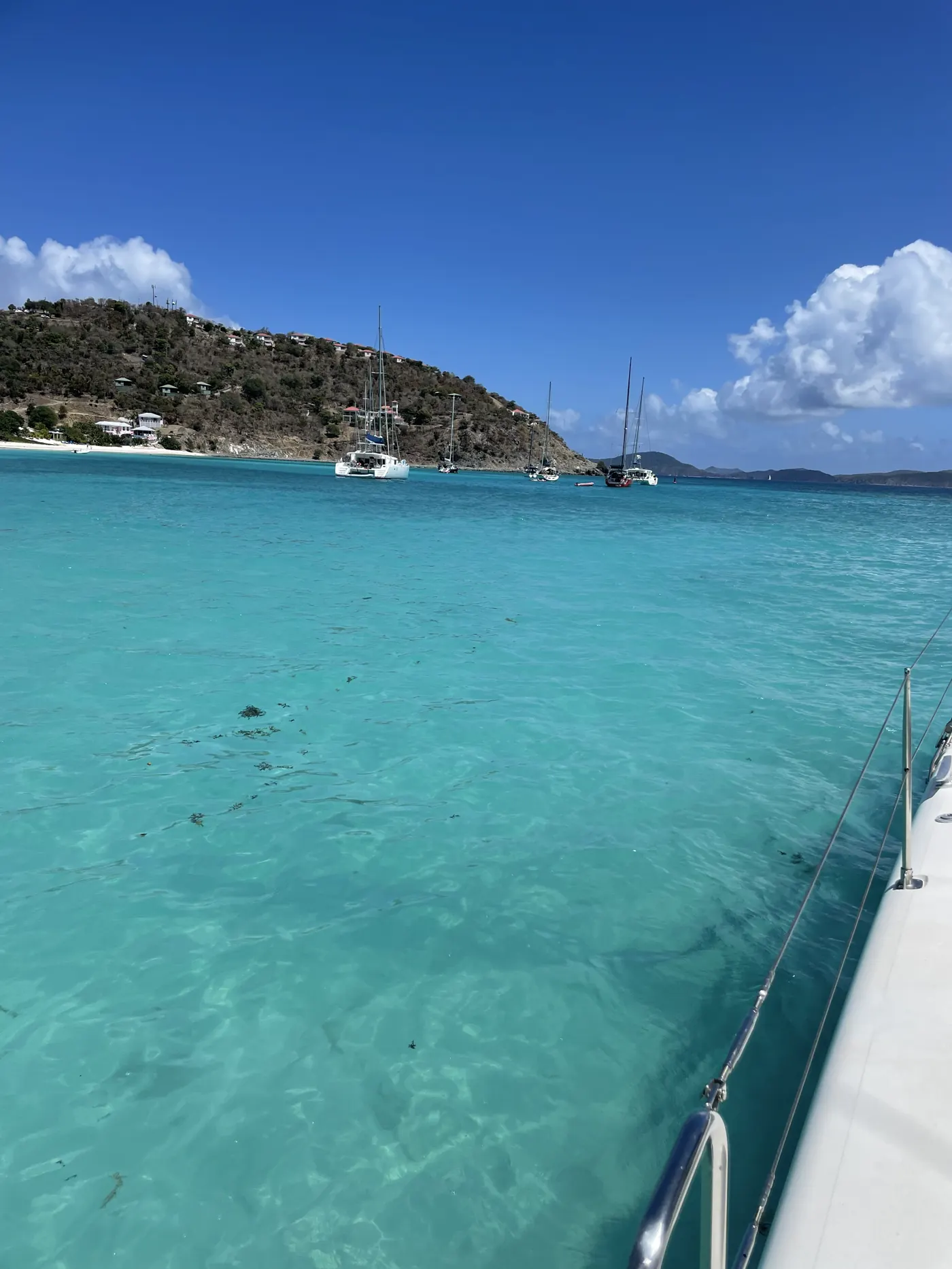 Bright turquoise water beside a catamaran with a green island behind