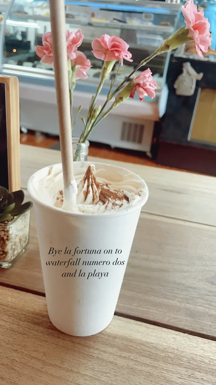 A takeaway cup decorated with pink flowers on a cafe counter