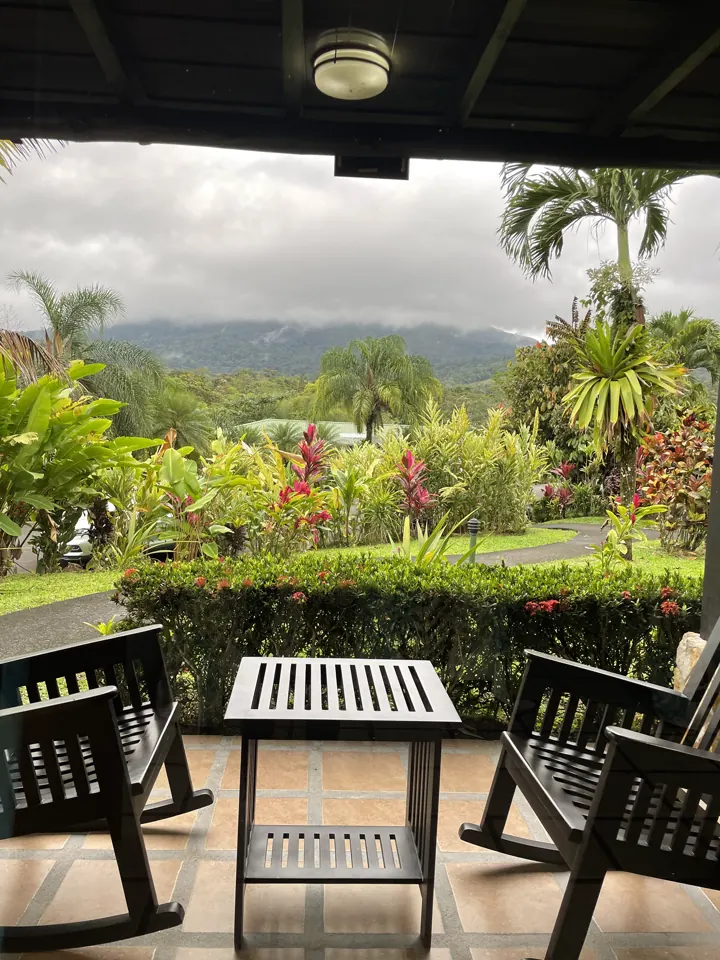 A covered porch with rocking chairs overlooking a tropical garden