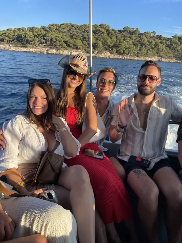 Group of friends in hats and sunglasses sitting on a boat on the water