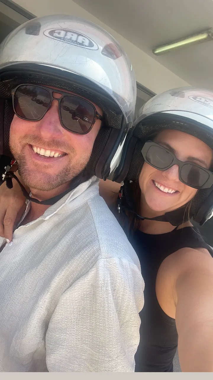 Colin and Angela in scooter helmets and sunglasses taking a selfie