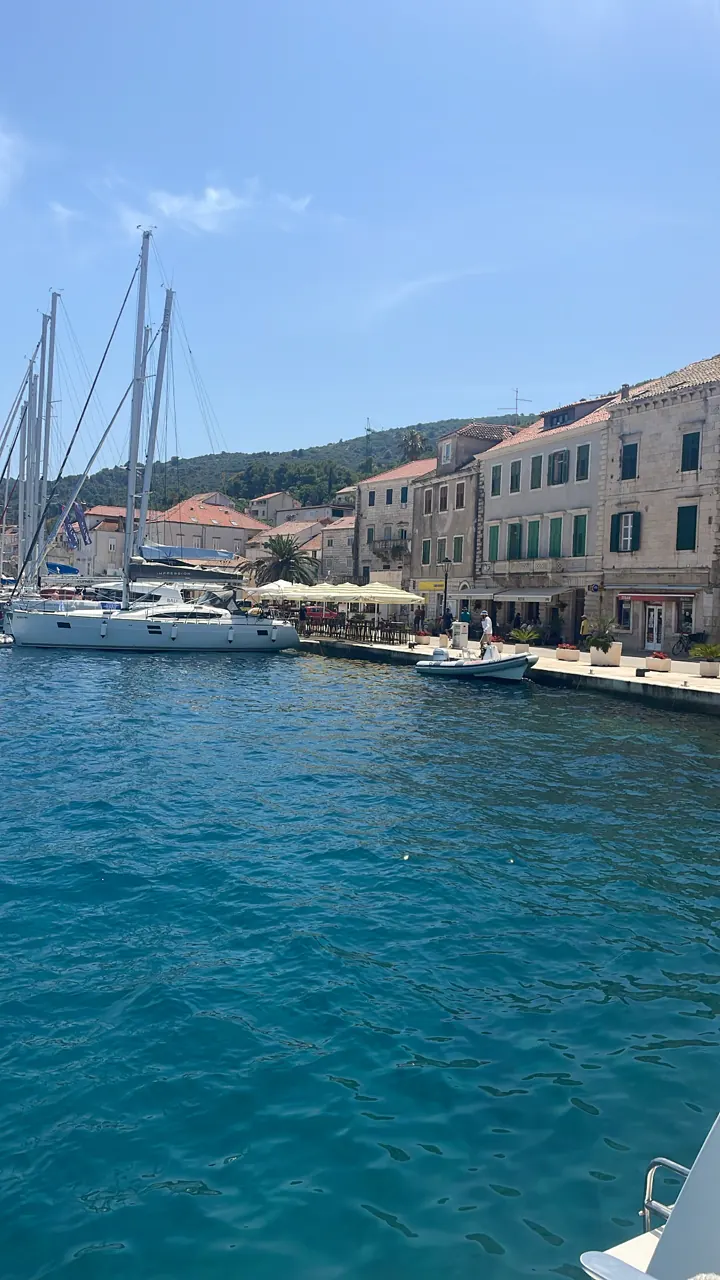 Sailboats and motorboats moored along the stone waterfront of Vis town under blue sky