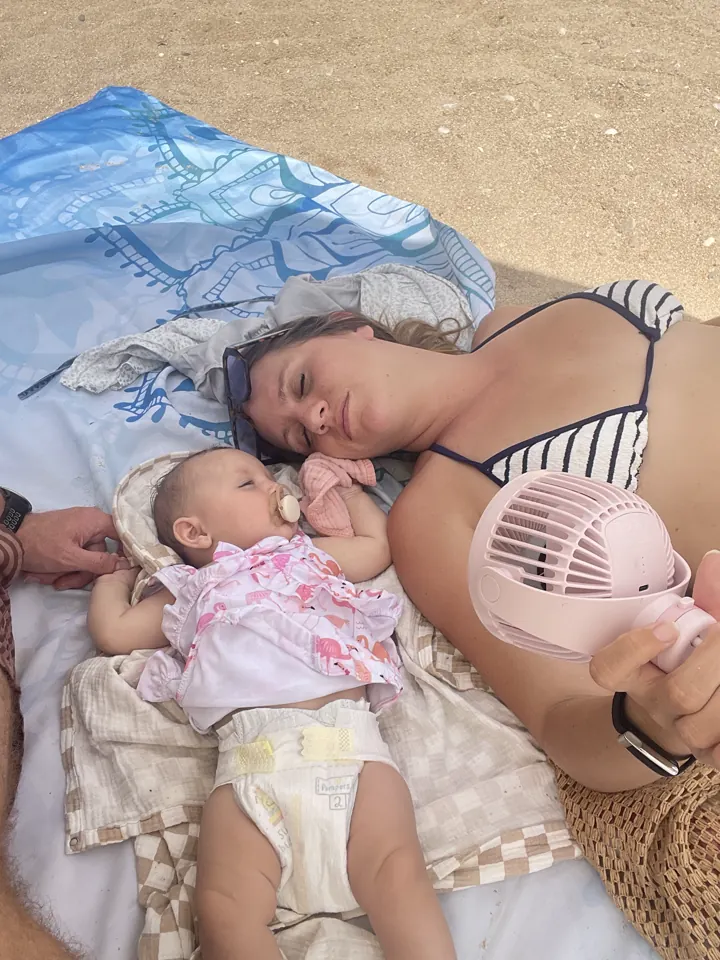 Angela and Andi on a beach towel with a little clip-on fan