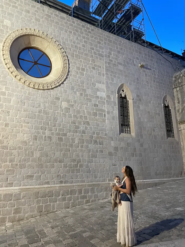 Angela holding Andi beside a stone church in Dubrovnik