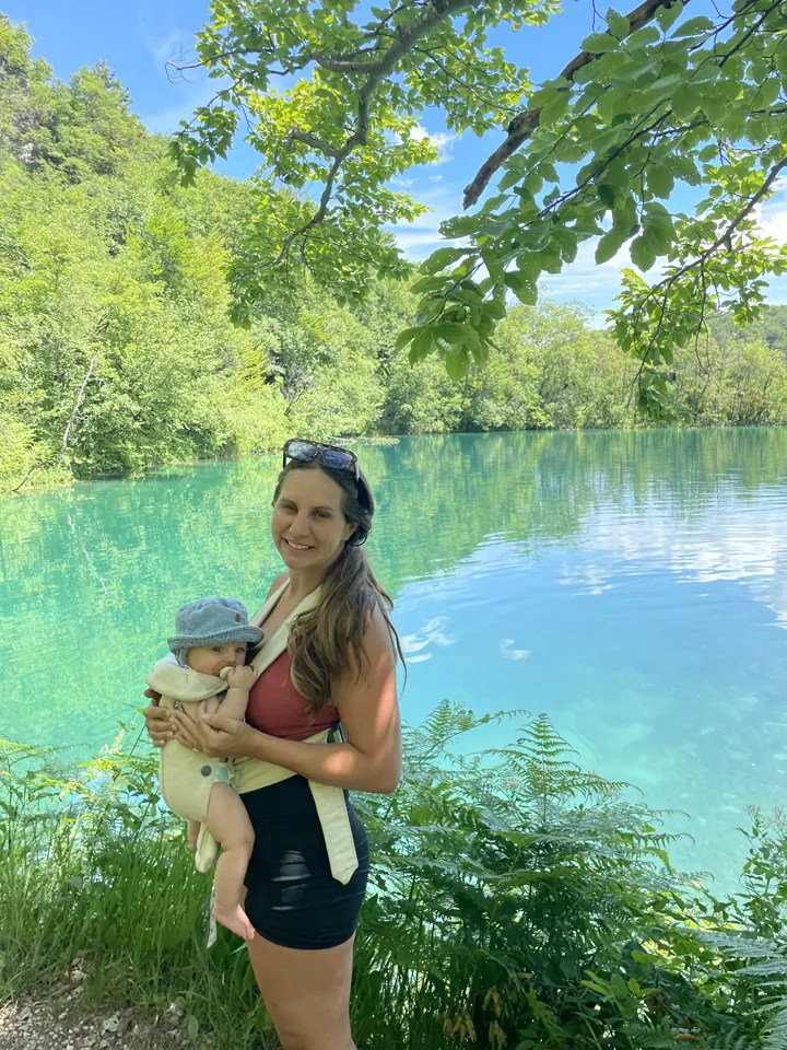 Angela with Andi in the carrier beside a turquoise lake at Plitvice
