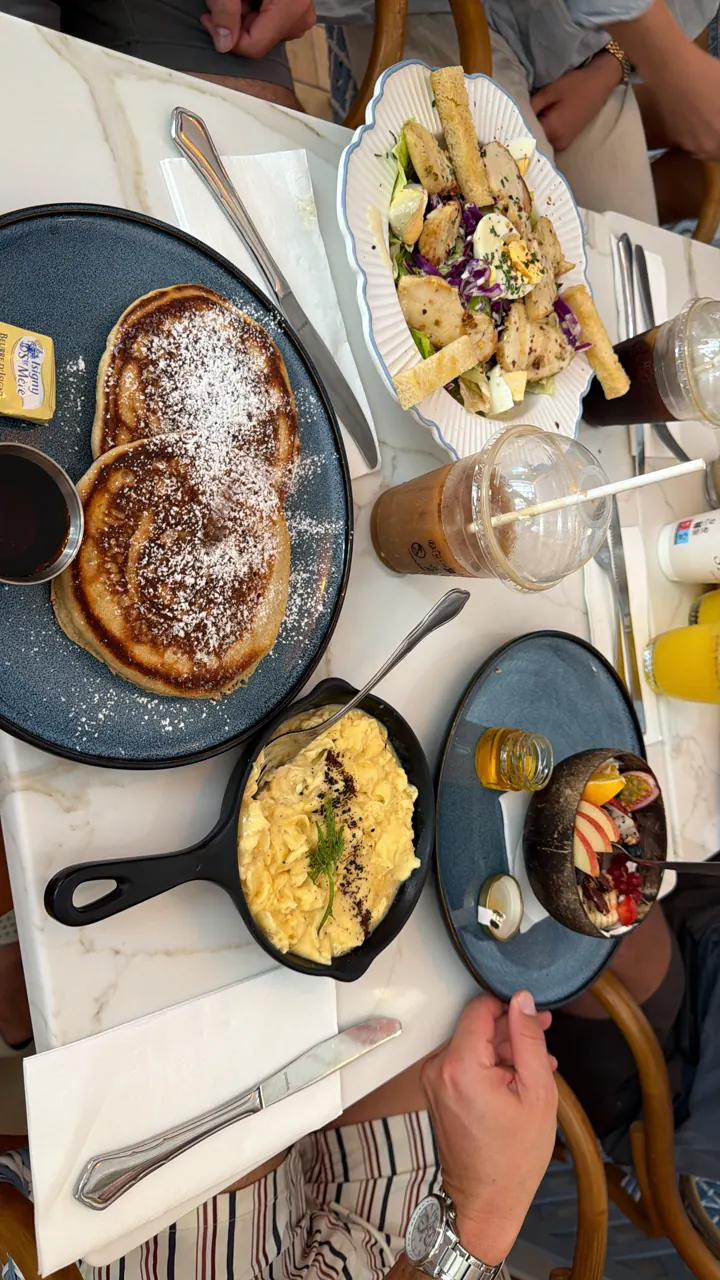 Overhead view of a brunch spread with pancakes, eggs in skillets and drinks