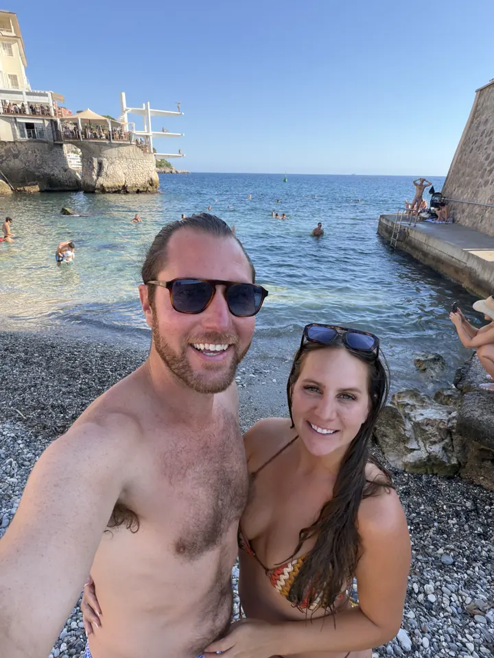 Colin and Angela taking a selfie on a pebble beach with the sea behind