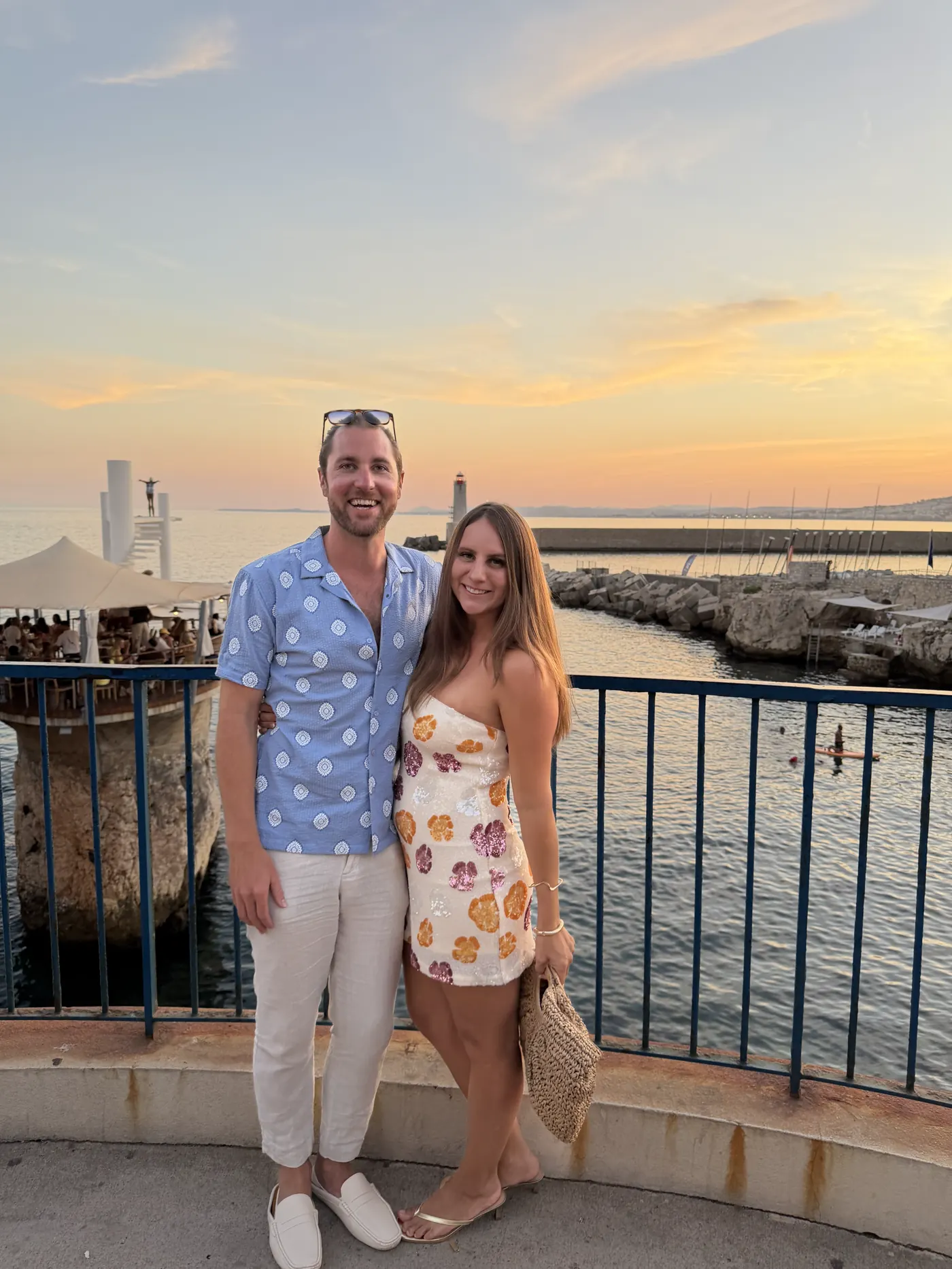 Colin and Angela standing at a seaside railing at sunset