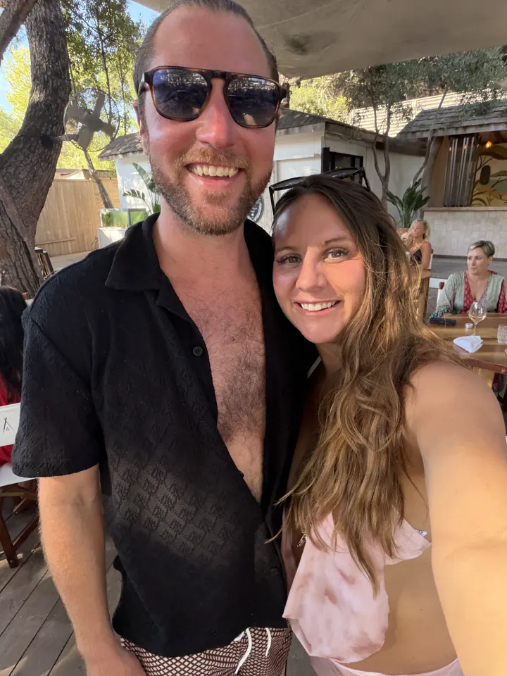 Colin and Angela smiling in a selfie at a beach club