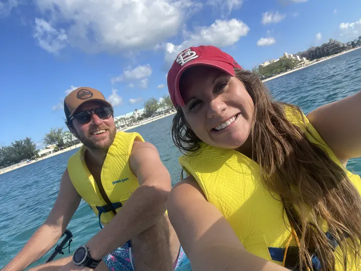A couple in life vests smiles while kayaking on the water
