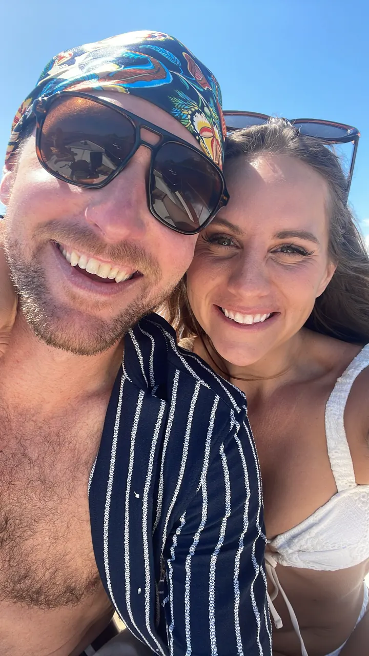 Colin in a bandana and sunglasses with Angela in a seaside selfie