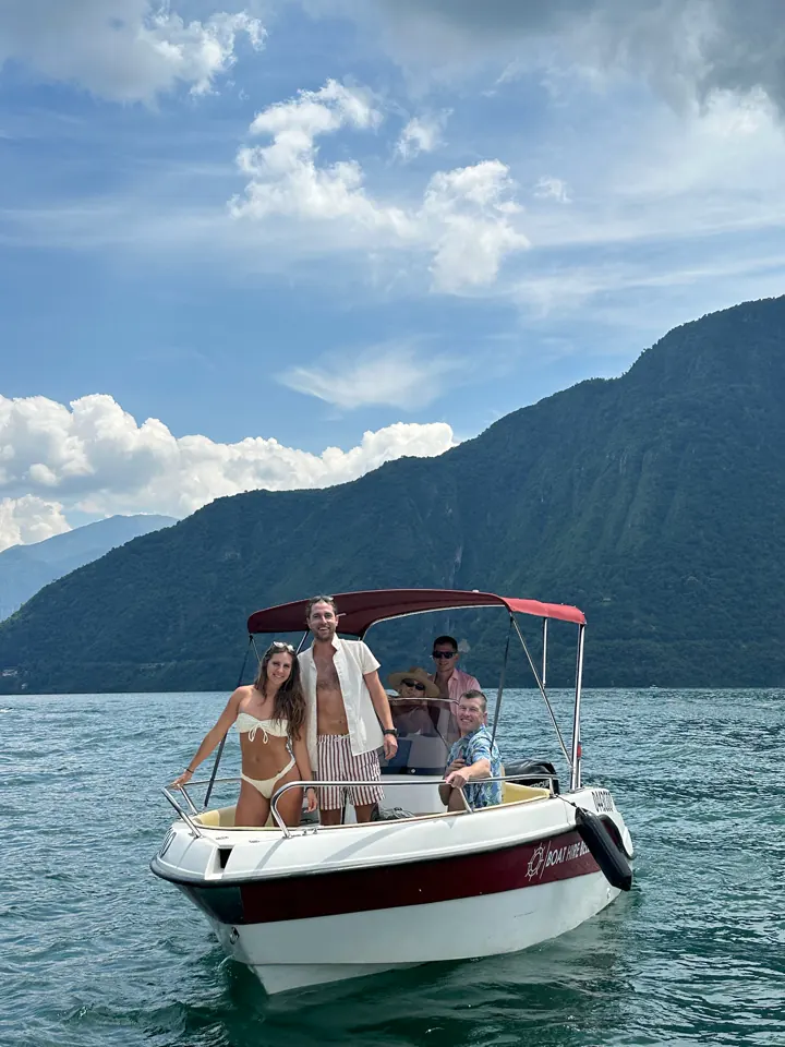 Small motorboat with passengers on Lake Como below mountains