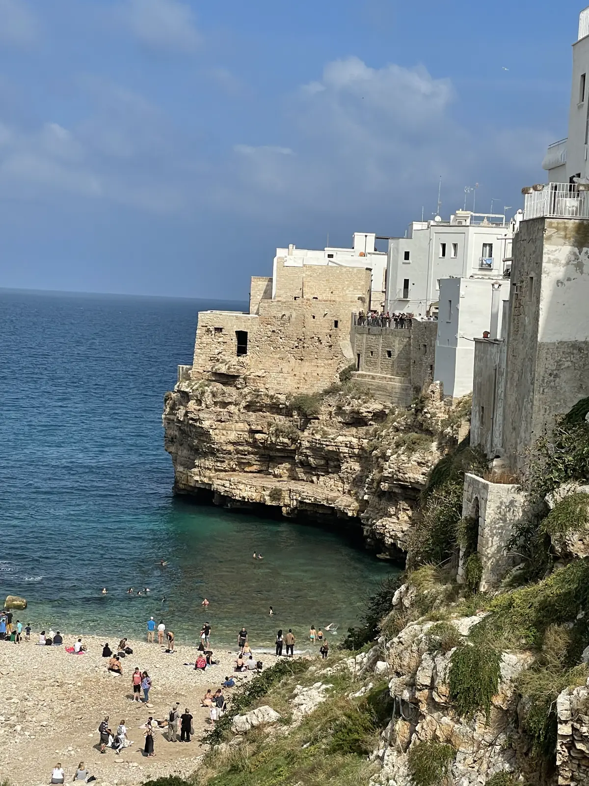 Whitewashed buildings on cliffs above a beach cove in Polignano a Mare