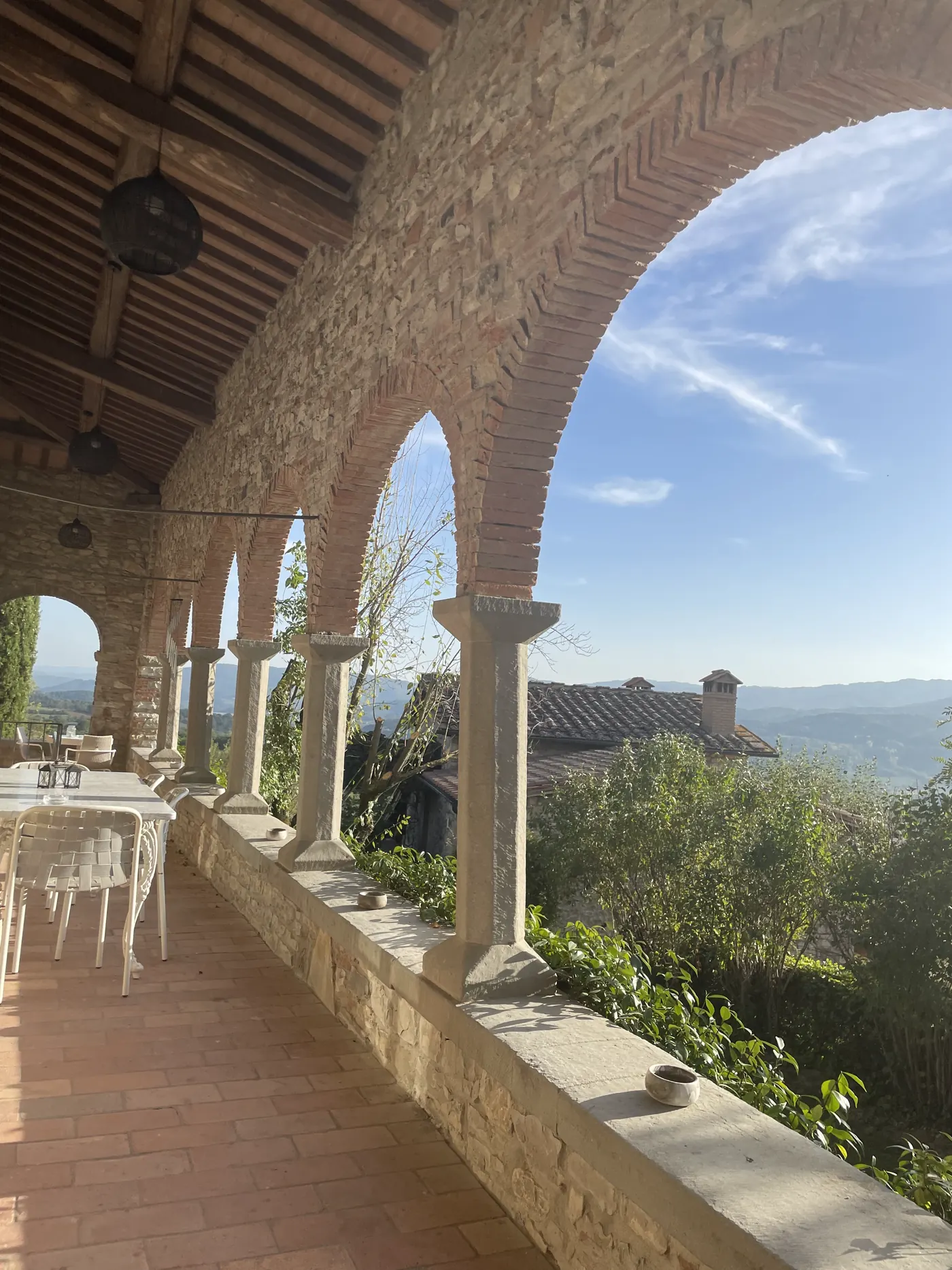 Stone arched loggia overlooking green Tuscan hills