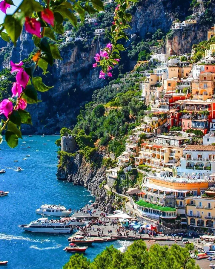 Colorful Positano buildings stacked on the cliff above boats and turquoise water