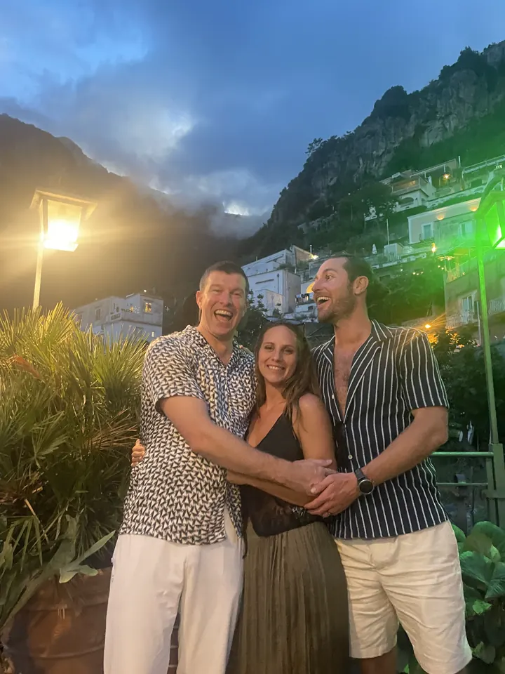 Colin and Angela with a friend on a lit terrace at dusk in Positano