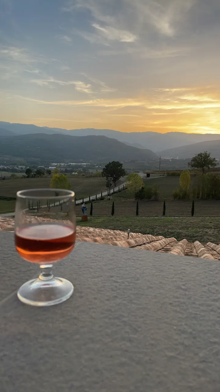 Amber cocktail on a ledge with a sunset over hills