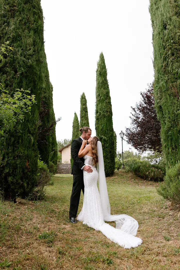 Bride and groom standing among tall cypress trees