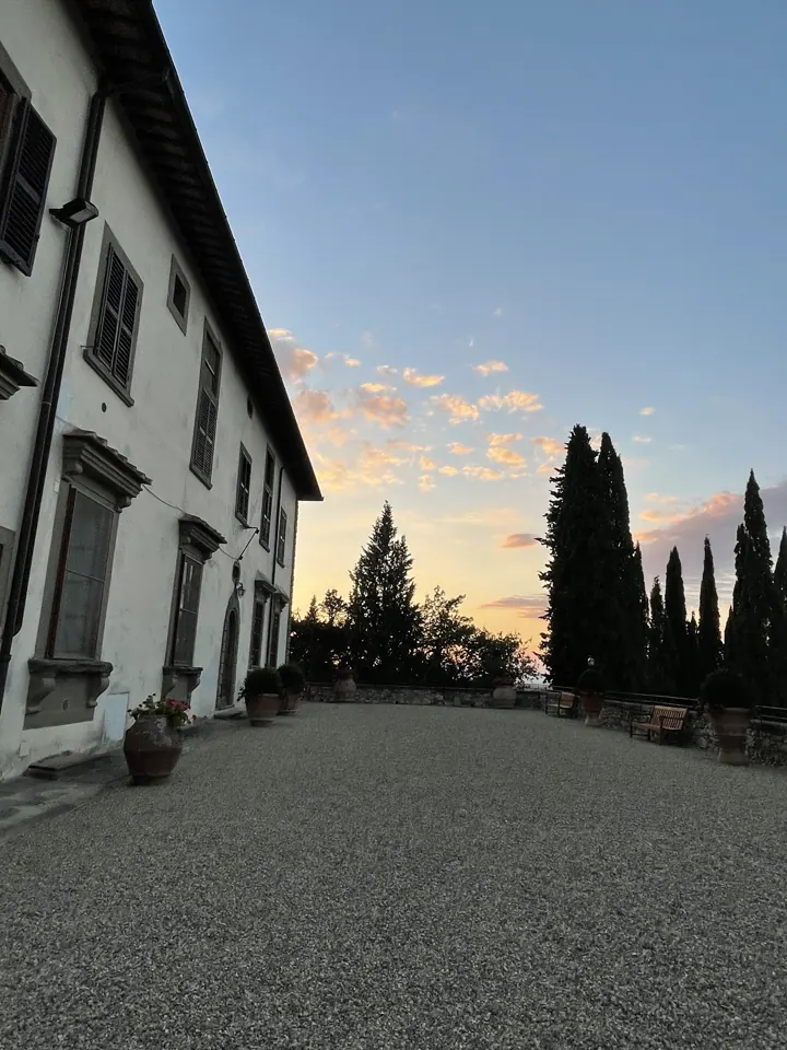 A Tuscan villa and a line of cypress trees at sunset
