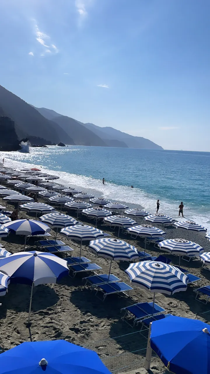 Rows of blue and white beach umbrellas along a Ligurian beach