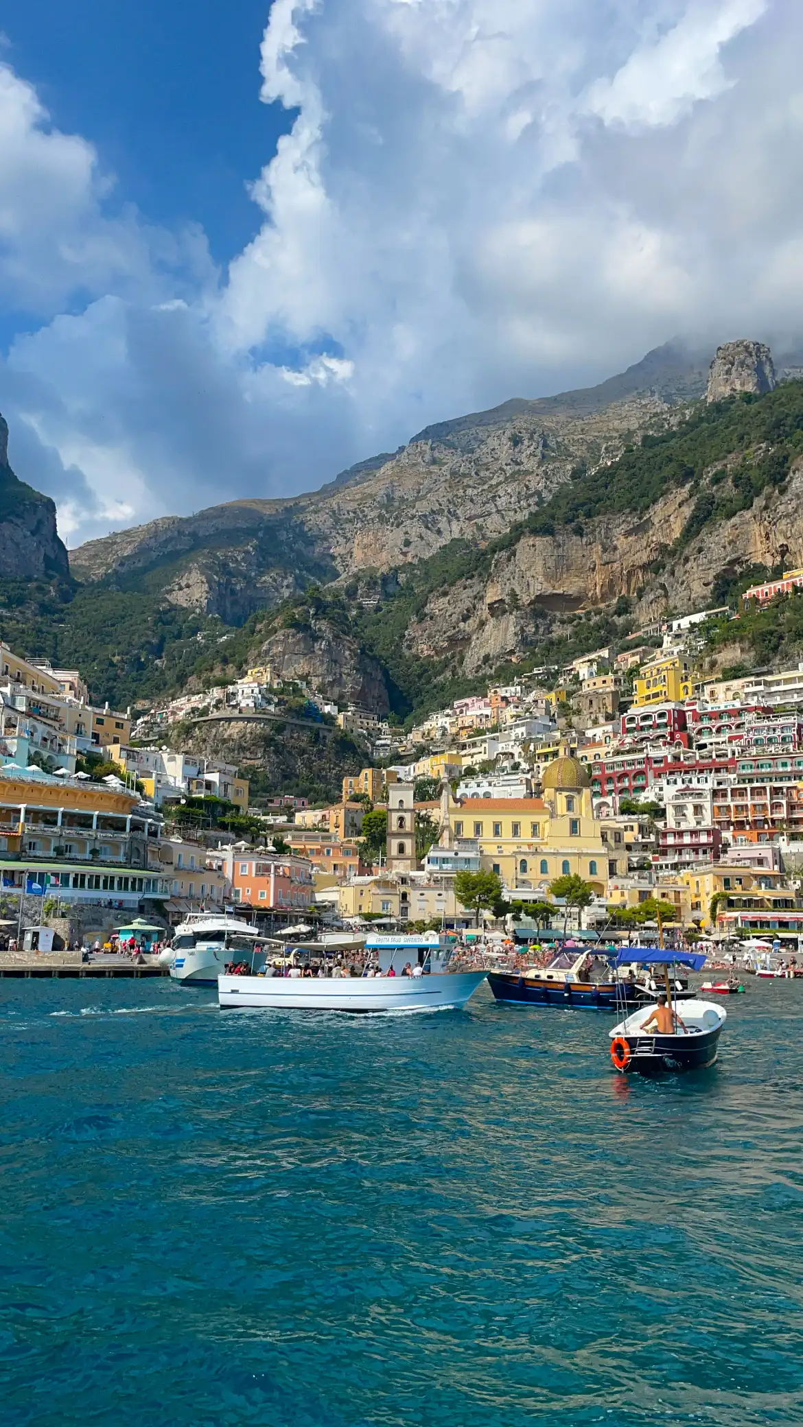Boats crowding the harbor below the colorful cliffside town of Positano