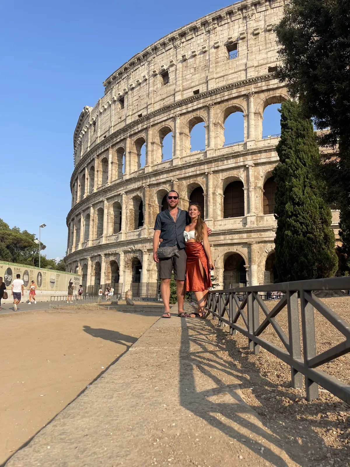 A couple standing in front of the Colosseum on a sunny afternoon
